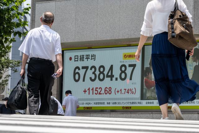 Pedestrians walk past an electronic quotation board displaying the Nikkei Stock Average on the Tokyo Stock Exchange in Tokyo on July 22, 2026. (Photo by Philip FONG / AFP)
