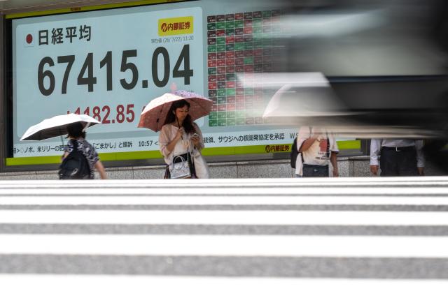Pedestrians walk past an electronic quotation board displaying the Nikkei Stock Average on the Tokyo Stock Exchange in Tokyo on July 22, 2026. (Photo by Philip FONG / AFP)
