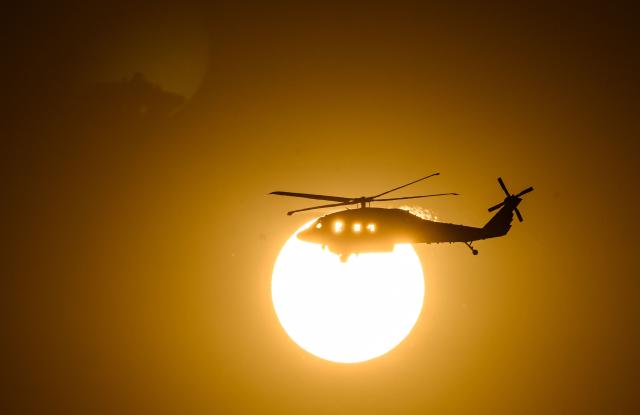 A CalFire helicopter crosses the sun on its way to make a water drop on Little Fire in Pleasanton, California on July 21, 2026. (Photo by Josh Edelson / AFP)