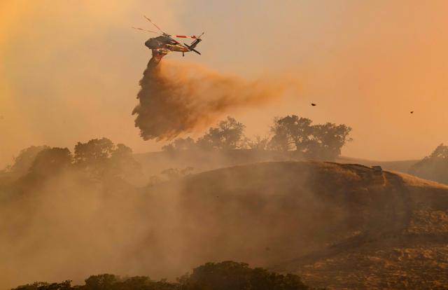 A helicopter drops water on Little Fire in Pleasanton, California on July 21, 2026. (Photo by Josh Edelson / AFP)