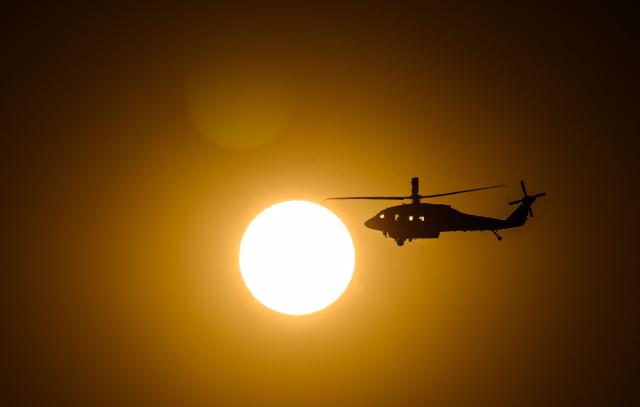A CalFire helicopter crosses the sun on its way to make a water drop on Little Fire in Pleasanton, California on July 21, 2026. (Photo by Josh Edelson / AFP)