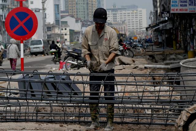 A worker ties reinforcement bars on a roadside in Hanoi on July 22, 2026. (Photo by Nhac NGUYEN / AFP)