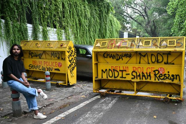 A Cockroach Janta Party (CJP) supporter sits at Jantar Mantar in New Delhi on July 22, 2026 during the ongoing protest to demand the resignation of India's Education Minister Dharmendra Pradhan over alleged NEET exam irregularities. (Photo by Sajjad HUSSAIN / AFP)