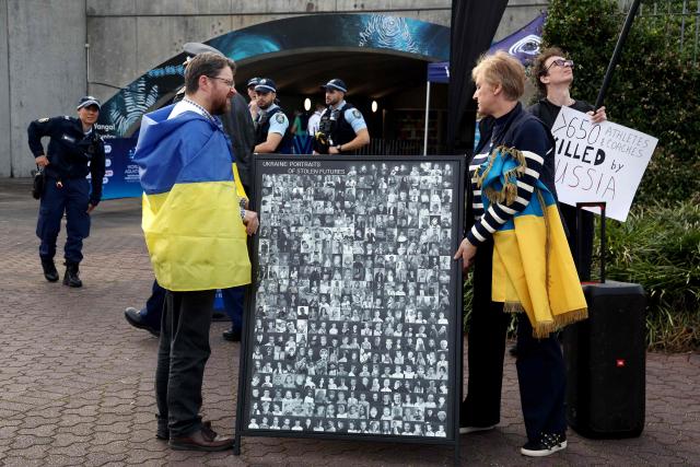 Police officers stand near members of the Ukrainian community holding flags and placards as they protest the inclusion of Russia in the 2026 World Aquatics Water Polo World Cup Finals outside the Sydney Aquatic Centre in Sydney on July 22, 2026. (Photo by DAVID GRAY / AFP)