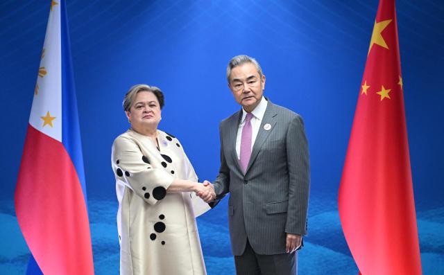 Philippine Secretary of Foreign Affairs Theresa Lazaro (L) shakes hands with China's Foreign Minister Wang Yi during their bilateral meeting on the sidelines of the Association of Southeast Asian Nations (ASEAN) Foreign Ministers' Meeting in Pasay, Metro Manila on July 22, 2026. (Photo by Ted ALJIBE / POOL / AFP)