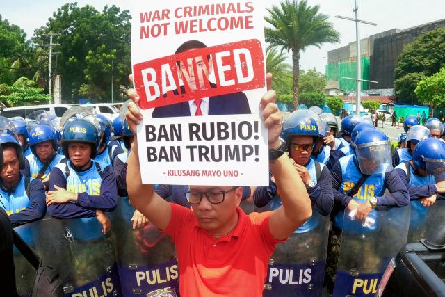 Police look on as a demonstrator holds up a placard protesting US Secretary of State Marco Rubio's visit to the Philippines to attend the Association of Southeast Asian Nations (ASEAN) Foreign Ministers' Meeting outside the meeting venue in Pasay, Metro Manila on July 22, 2026. (Photo by Bullit MARQUEZ / AFP)