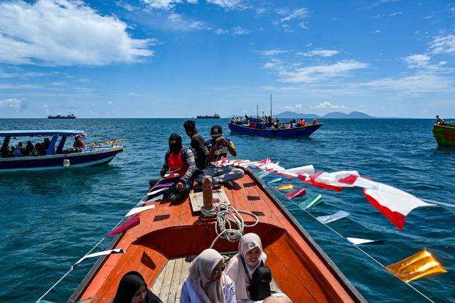 Indonesian fishermen take part in the traditional festival known as "Kenduri Laot," a maritime feast held as an expression of gratitude for the ocean, off the coast of Banda Aceh on July 22, 2026. (Photo by CHAIDEER MAHYUDDIN / AFP)