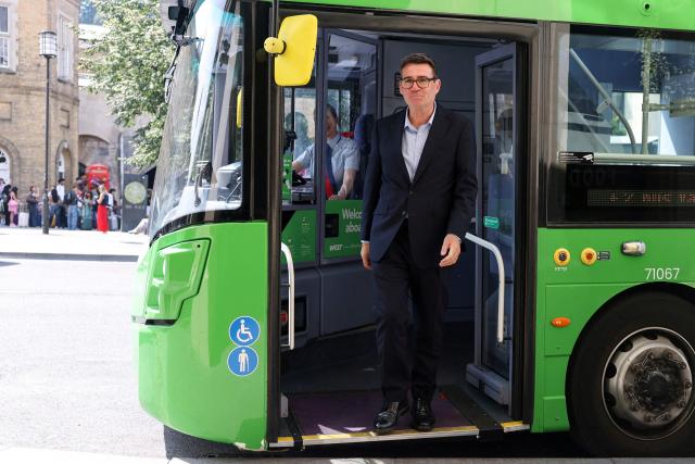 Britain's Prime Minister Andy Burnham disembarks a bus after a ride in central Bath, western England, on July 22, 2026. Burnham, who became prime minister on July 20, pledged on July 22 to ease cost-of-living pressures, unveiling a tax cut on household electricity prices and a £2 (2.70 USD) cap on single bus fares in his first days in the job. (Photo by Toby Melville / POOL / AFP)
