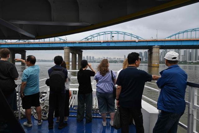 People look at the view from a ferry on the Han River in Seoul on July 22, 2026. (Photo by GREG BAKER / AFP)