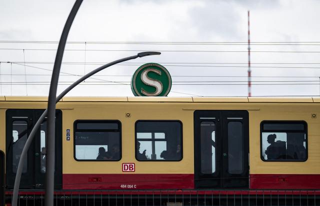 An S-Bahn train pulls into an elevated S-Bahn station operated by German railway giant Deutsche Bahn, with the Berlin TV Tower (Fernsehturm) in the background in Berlin on a cloudy chilly summer day, on July 22, 2026. (Photo by John MACDOUGALL / AFP)
