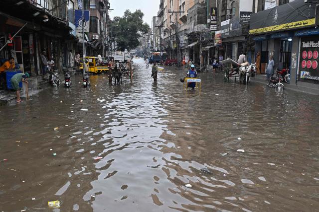Locals look at a flooded street after heavy rainfall in Lahore on July 22, 2026. (Photo by Arif ALI / AFP)