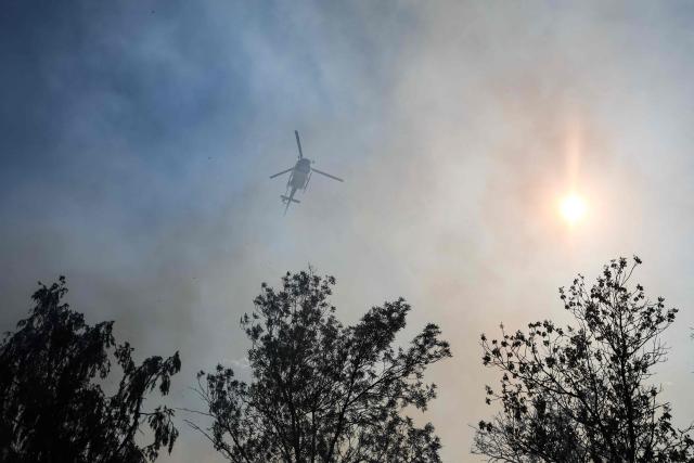 A helicopter flies over a burning area as a wildfire flares up again in Ponteves, southeastern France on July 22, 2026. Firefighters have managed to contain the fierce blaze that swept through 2,550 hectares in the Var in less than a day, forcing the evacuation of around 500 people, and which on July 22, 2026 is still burning across a vast mountainside. (Photo by Thibaud MORITZ / AFP)