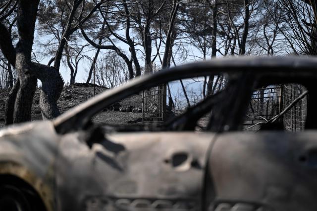 This photograph shows the wreck of a car in a burnt area as a wildfire flares up again in Ponteves, southeastern France on July 22, 2026. Firefighters have managed to contain the fierce blaze that swept through 2,550 hectares in the Var in less than a day, forcing the evacuation of around 500 people, and which on July 22, 2026 is still burning across a vast mountainside. (Photo by Frederic Dides / AFP)