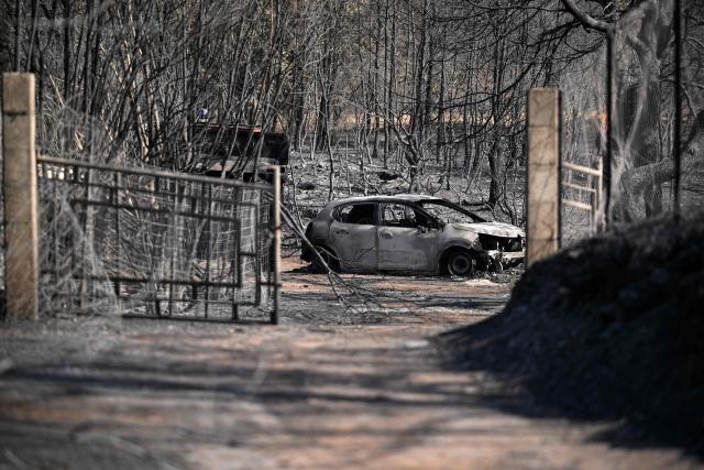 This photograph shows the wreck of a car in a burnt area as a wildfire flares up again in Ponteves, southeastern France on July 22, 2026. Firefighters have managed to contain the fierce blaze that swept through 2,550 hectares in the Var in less than a day, forcing the evacuation of around 500 people, and which on July 22, 2026 is still burning across a vast mountainside. (Photo by Frederic Dides / AFP)