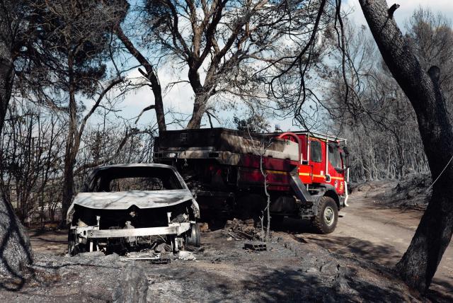 This photograph shows a burnt car and a firefighter vehicle in a burnt area as a wildfire flares up again in Ponteves, southeastern France on July 22, 2026. Firefighters have managed to contain the fierce blaze that swept through 2,550 hectares in the Var in less than a day, forcing the evacuation of around 500 people, and which on July 22, 2026 is still burning across a vast mountainside. (Photo by Frederic DIDES / AFP)