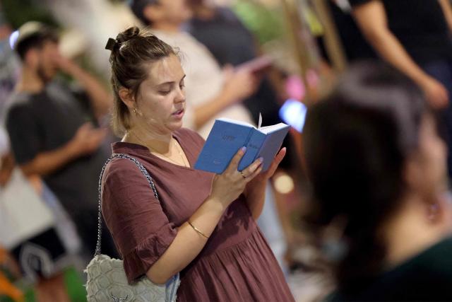 Religious and secular Israelis gather to read excerpts from the biblical Book of Lamentations in the Israeli coastal city of Tel Aviv on July 22, 2026, during the annual vigil of Tisha B'Av (the ninth day of Av) commemorating the destruction of the first and second temples in Jerusalem by the ancient Babylonians and Romans respectively. (Photo by JACK GUEZ / AFP)