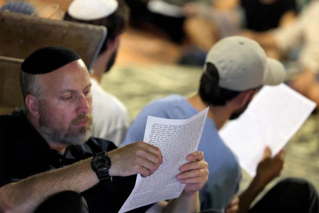 Religious and secular Israelis gather to read excerpts from the biblical Book of Lamentations in Tel Aviv on July 22, 2026, during the annual vigil of Tisha B'Av (the ninth day of Av) commemorating the destruction of the first and second temples in Jerusalem by the ancient Babylonians and Romans respectively. (Photo by JACK GUEZ / AFP)