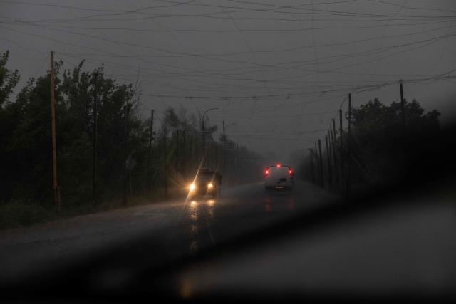 Cars drive through heavy rain along a road covered with anti-drone nets, in the Kharkiv region on July 21, 2026, amid the Russian invasion of Ukraine. (Photo by Roman PILIPEY / AFP)