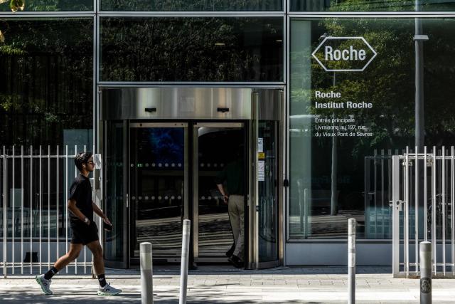 A pedestrian walks past the French office of Roche, a Swiss multinational holding healthcare company that operates worldwide under a pharmaceutical and diagnostics divisions, in Boulogne-Billancourt, outside Paris on July 22, 2026.  (Photo by Xavier GALIANA / AFP)