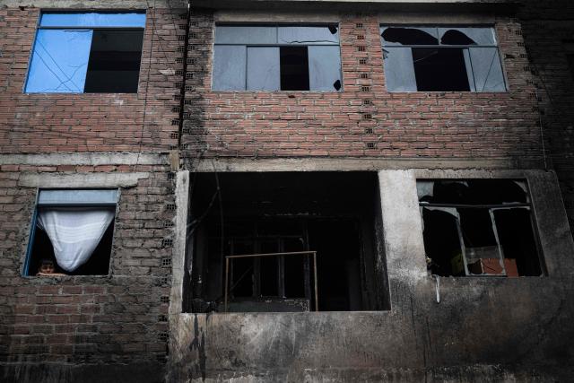 A child looks out from the window of a house next to one where a fire killed ten people in Lima on July 22, 2026. A fire in a low-income neighborhood in Lima killed 10 people and destroyed two homes, Peru's civil defense reported. Two more people were injured, the INDECI civil defense institute wrote in a social media post. (Photo by ERNESTO BENAVIDES / AFP)