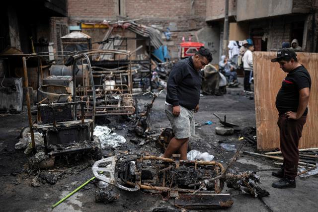 People clear debris from the site of a fire that killed ten people in Lima on July 22, 2026. A fire in a low-income neighborhood in Lima killed 10 people and destroyed two homes, Peru's civil defense reported. Two more people were injured, the INDECI civil defense institute wrote in a social media post. (Photo by ERNESTO BENAVIDES / AFP)