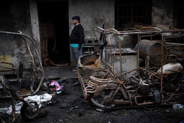 A man stands next to debris at the site of a fire that killed ten people in Lima on July 22, 2026. A fire in a low-income neighborhood in Lima killed 10 people and destroyed two homes, Peru's civil defense reported. Two more people were injured, the INDECI civil defense institute wrote in a social media post. (Photo by ERNESTO BENAVIDES / AFP)