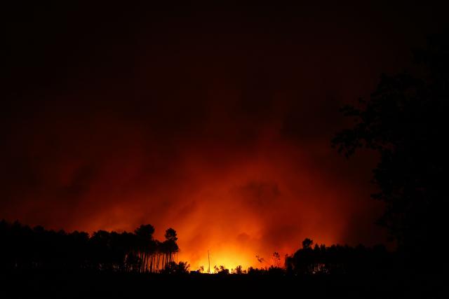 This photograph shows a wooden area engulfed in flames during a wildfire in Le Porge, south-western France on July 22, 2026. A fast-moving wildfire has burned 900 hectares north of Arcachon Bay in southwestern France, forcing the evacuation of more than 4,000 residents and tourists. The blaze, described by firefighters as exceptionally intense, spread sixfold in less than three hours through dense pine forests and is now advancing toward Ares and Lege-Cap-Ferret. The area was previously devastated by major wildfires in 2022. (Photo by ROMAIN PERROCHEAU / AFP)