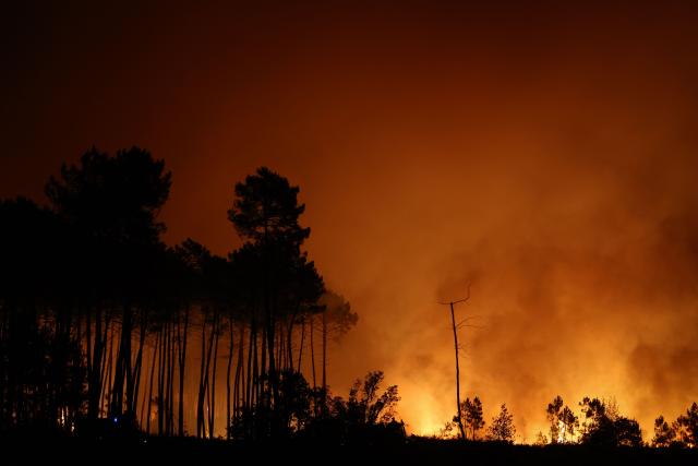 This photograph shows a wooden area engulfed in flames during a wildfire in Le Porge, south-western France on July 22, 2026. A fast-moving wildfire has burned 900 hectares north of Arcachon Bay in southwestern France, forcing the evacuation of more than 4,000 residents and tourists. The blaze, described by firefighters as exceptionally intense, spread sixfold in less than three hours through dense pine forests and is now advancing toward Ares and Lege-Cap-Ferret. The area was previously devastated by major wildfires in 2022. (Photo by ROMAIN PERROCHEAU / AFP)