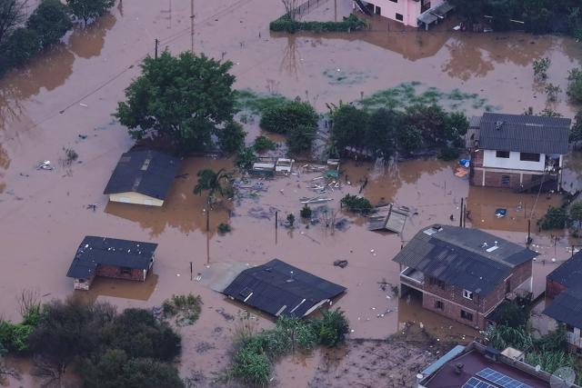 This aerial view shows houses submerged by floodwaters from the overflowing Taquari River near the boundary between the Centro and Planalto neighborhoods in Encantado, Rio Grande do Sul state, Brazil, on July 22, 2026. (Photo by Gustavo Ghisleni / AFP)