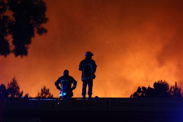 Firefighters monitor a wildfire in Le Porge, south-western France on July 22, 2026. A fast-moving wildfire has burned 900 hectares north of Arcachon Bay in southwestern France, forcing the evacuation of more than 4,000 residents and tourists. The blaze, described by firefighters as exceptionally intense, spread sixfold in less than three hours through dense pine forests and is now advancing toward Ares and Lege-Cap-Ferret. The area was previously devastated by major wildfires in 2022. (Photo by ROMAIN PERROCHEAU / AFP)