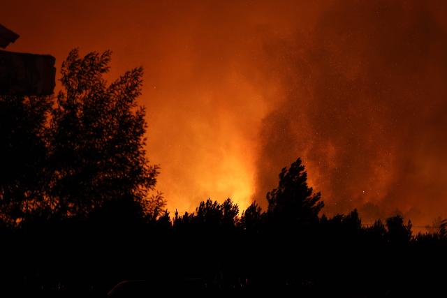 A wildfire rages through a forestry area in Le Porge, south-western France early on July 23, 2026. A fast-moving wildfire has burned 900 hectares north of Arcachon Bay in southwestern France, forcing the evacuation of more than 4,000 residents and tourists. The blaze, described by firefighters as exceptionally intense, spread sixfold in less than three hours through dense pine forests and is now advancing toward Ares and Lege-Cap-Ferret. The area was previously devastated by major wildfires in 2022. (Photo by ROMAIN PERROCHEAU / AFP)