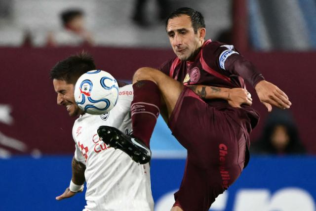 Cienciano's forward #10 Alejandro Hohberg (L) and Lanus' defender #24 Carlos Izquierdoz fight for the ball during the first leg of the Copa Sudamericana knockout round play-off football match between Argentina's Lanus and Peru's Cienciano, at the Ciudad de Lanus stadium, in Lanus, Buenos Aires province, Argentina on July 22, 2026. (Photo by Luis ROBAYO / AFP)