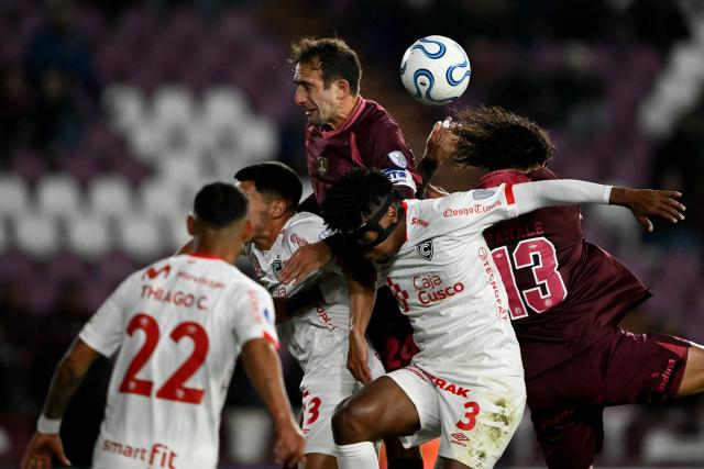 Lanus' defender #24 Carlos Izquierdoz (C) jumps to head the ball with Cienciano's Paraguayan defender #13 Claudio Nunez (L), Cienciano's Ecuadorean defender #03 Kevin Becerra and Lanus' Paraguayan defender #13 Jose Maria Canale during the first leg of the Copa Sudamericana knockout round play-off football match between Argentina's Lanus and Peru's Cienciano, at the Ciudad de Lanus stadium, in Lanus, Buenos Aires province, Argentina on July 22, 2026. (Photo by Luis ROBAYO / AFP)