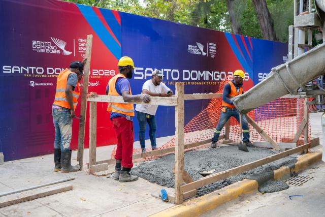 Workers pour concrete on a sidewalk during preparations for the XXV Central American and Caribbean Games in Santo Domingo on July 22, 2026. The XXV Central American and Caribbean Games - Santo Domingo 2026, will be held from July 24 to August 8, 2026, in the Dominican Republic. (Photo by Francesco SPOTORNO / AFP)