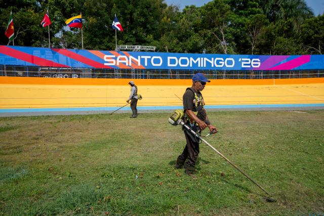 Workers mow the grass on a field during preparations for the XXV Central American and Caribbean Games in Santo Domingo on July 22, 2026. The XXV Central American and Caribbean Games - Santo Domingo 2026, will be held from July 24 to August 8, 2026, in the Dominican Republic. (Photo by Francesco SPOTORNO / AFP)