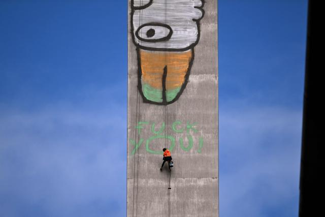EDITORS NOTE: Graphic content / Abseilers prepare to paint over Pam the Bird graffiti on Melbourne's Bolte Bridge on July 23, 2026. The graffiti was spray-painted on one of the bridge's 140-metre-tall pylons by alleged vandal Jack Gibson-Burrell and it is expected to take several days, taking 100 litres of surface preparation, primer and paint. (Photo by William WEST / AFP)