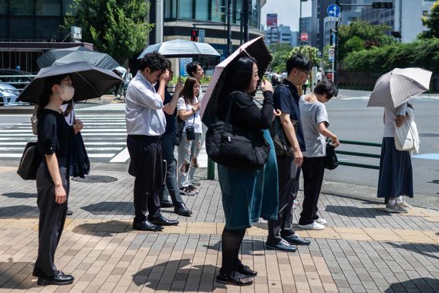 People carry umbrellas to shelter from the sun in Tokyo on July 23, 2026. Tokyo recorded the most daily heat-related hospitalisations since 2010, emergency services said as Japan sweltered in a severe heatwave, with one person dead and four in a critical condition. (Photo by Andrew CABALLERO-REYNOLDS / AFP)