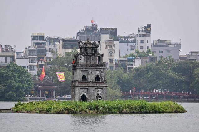 A worker renovates the "Thap Rua" (Turtle Tower) at Hoan Kiem Lake in Hanoi on July 23, 2026. (Photo by Nhac NGUYEN / AFP)