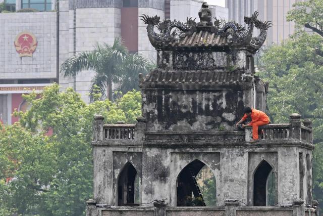 A worker renovates the "Thap Rua" (Turtle Tower) at Hoan Kiem Lake in Hanoi on July 23, 2026. (Photo by Nhac NGUYEN / AFP)