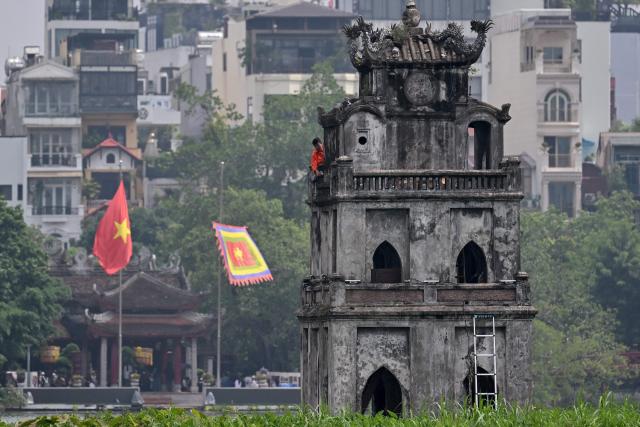 A worker renovates the "Thap Rua" (Turtle Tower) at Hoan Kiem Lake in Hanoi on July 23, 2026. (Photo by Nhac NGUYEN / AFP)