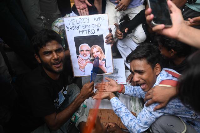 Cockroach Janta Party (CJP) supporters hold a placard portraying Italian Prime Minister Giorgia Meloni with Indian Prime Minister Narendra Modi, at Jantar Mantar in New Delhi on July 23, 2026 during the ongoing protest to demand the resignation of India's Education Minister Dharmendra Pradhan over alleged NEET exam irregularities. (Photo by Arun SANKAR / AFP)