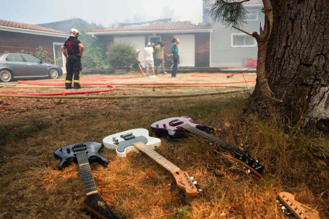 This photograph shows guitars as firefighters try to extinguishing a fire burning a house in Le Porge, southwestern France on July 23, 2026. A highly virulent wildfire has swept through more than 2,000 hectares since July 22, 2026 near the Arcachon Basin (Gironde), where nearly 12,000 residents and tourists have been evacuated in total from this area of the Landes de Gascogne forest, already devastated by flames in 2022. (Photo by ROMAIN PERROCHEAU / AFP)