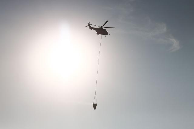 This photograph shows a helicopter carrying water over a forest hit by a wildfire near Cotignac, southeastern France on July 23, 2026. Violent forest fires, fanned by wind and high temperatures, are raging in several regions of Southern Europe including Italy, Spain, and France where thousands of people were evacuated from a tourist area on July 23, 2026. The forests catch fire all the more easily as vegetation and soil have been extremely dry for months, a drought worsened by the exceptional heatwaves that swept across the continent in June and July and it is indeed climate change, caused primarily by the continued burning of oil, coal, and gas, that is making the current drought more severe, climate scientists from the World Weather Attribution group concluded in a study published July 23, 2026. (Photo by Thibaud MORITZ / AFP)