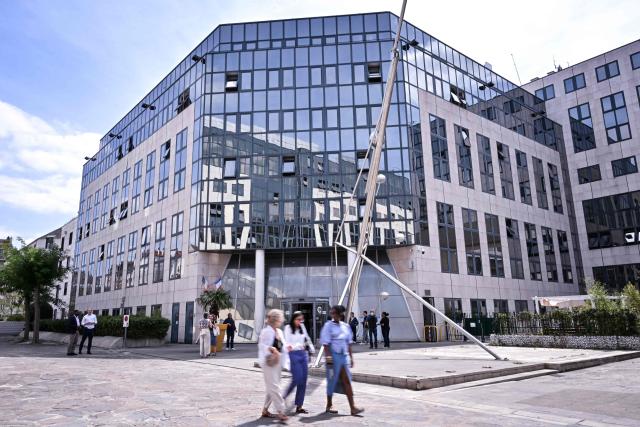 Pedestrians walk past the Office Francais de la Biodiversite - OFB (French Office for Biodiversity) displayed on the facade of its' headquarters, in Vincennes, suburb of Paris on July 23, 2026. (Photo by Lou BENOIST / AFP)