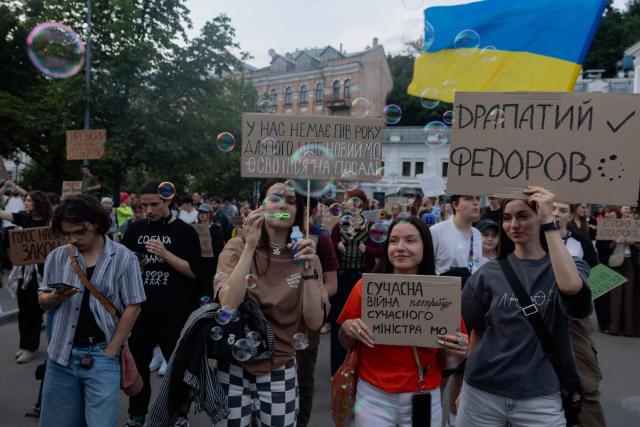Protesters hold placards during on the eighth day of a demonstration against Ukraine's President's decision to dismiss Ukraine's former Defence Minister, in Kyiv on July 23, 2026, amid the Russian invasion of Ukraine. Ukraine's ex-defence minister -- whose ousting trigged a week of protests and forced out the country's commander-in-chief -- said on July 23, 2026, he was rejecting offers by Ukraine's President for a new role. (Photo by Tetiana DZHAFAROVA / AFP)
