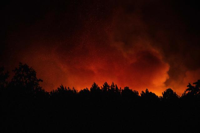 A wildfire rages on a forest close to a residential area near Lege-Cap-Ferret, southwestern France, on July 23, 2026. A highly virulent wildfire has swept through more than 3700 hectares since July 22, 2026 near the Arcachon Basin (Gironde), where nearly 20,000 residents and tourists have been evacuated in total from this area of the Landes de Gascogne forest, already devastated by flames in 2022. (Photo by JULIEN DE ROSA / AFP)