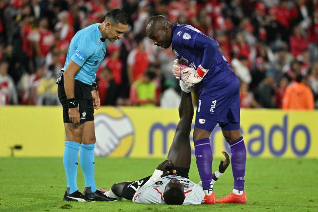 Caracas' Colombian forward #27 Sebastian Gonzalez receives assistance from Santa Fe's goalkeeper #01 Andres Mosquera Marmolejo during the first leg of the Copa Sudamericana knockout round play-off football match between Colombia's Independiente Santa Fe and Venezuela's Caracas, at the Nemesio Camacho 'El Campin' stadium in Bogota, on July 23, 2026. (Photo by Luis ACOSTA / AFP)