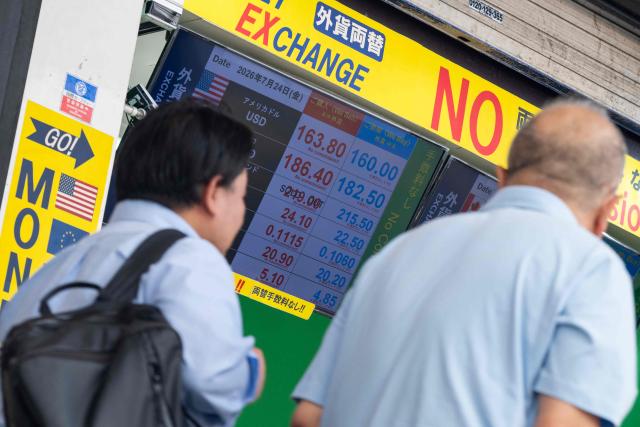 Two men walk past a display showing currency rates at a money exchange in Shinjuku district in Tokyo on July 24, 2026. Core inflation accelerated in Japan in June, official data showed as the Middle East war and a weak yen pushed up prices for consumers in the world's fourth-biggest economy. A falling yen, which overnight hit a fresh four-decade low against the US dollar, also increases the cost of imports like oil and food for resource-poor Japan. (Photo by Andrew CABALLERO-REYNOLDS / AFP)