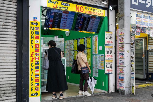 Two woman look at the currency rates at a money exchange in Shinjuku district in Tokyo on July 24, 2026. Core inflation accelerated in Japan in June, official data showed as the Middle East war and a weak yen pushed up prices for consumers in the world's fourth-biggest economy. A falling yen, which overnight hit a fresh four-decade low against the US dollar, also increases the cost of imports like oil and food for resource-poor Japan. (Photo by Andrew CABALLERO-REYNOLDS / AFP)