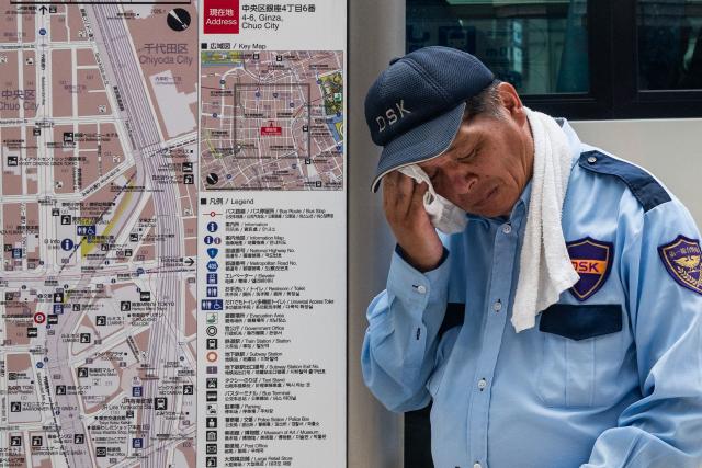 A security guard wipes his face on a hot day in Tokyo on July 24, 2026. (Photo by Andrew CABALLERO-REYNOLDS / AFP)